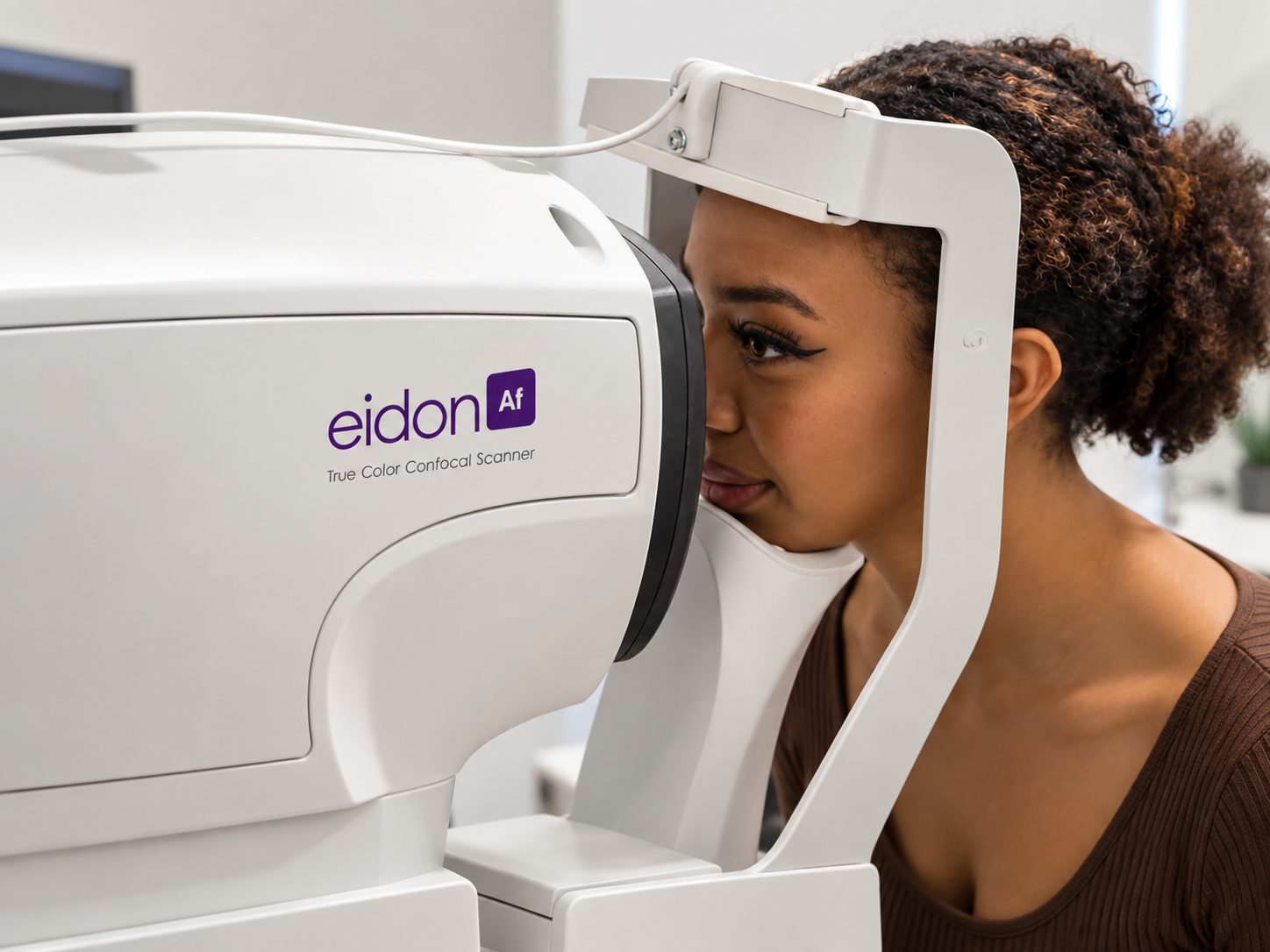 A patient looking into a retinal imaging scanner during an eye exam.
