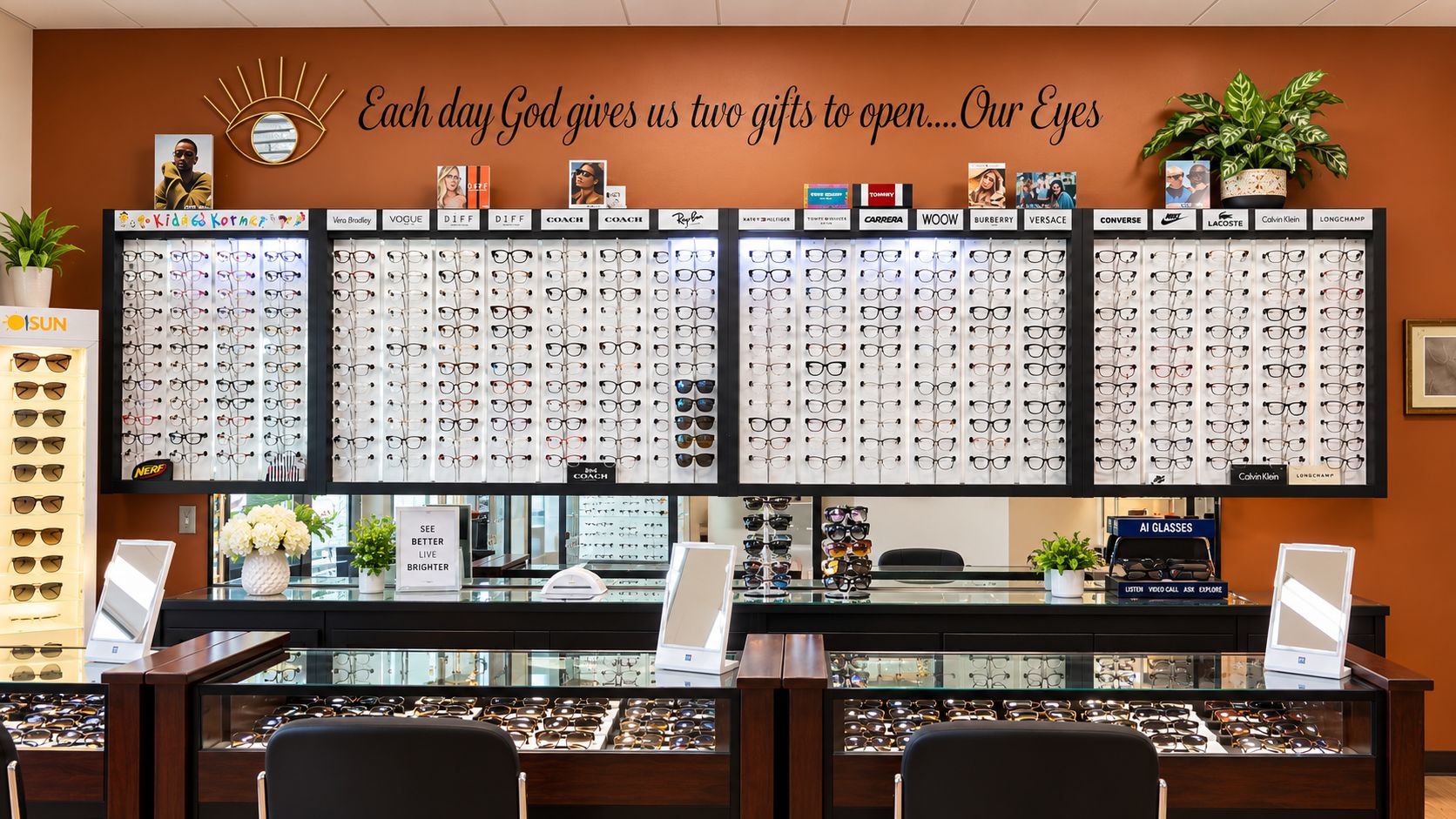 The practice’s lit frame wall of designer eyeglasses beneath the inscription “Each day God gives us two gifts to open… Our Eyes,” with glass display counters in front.